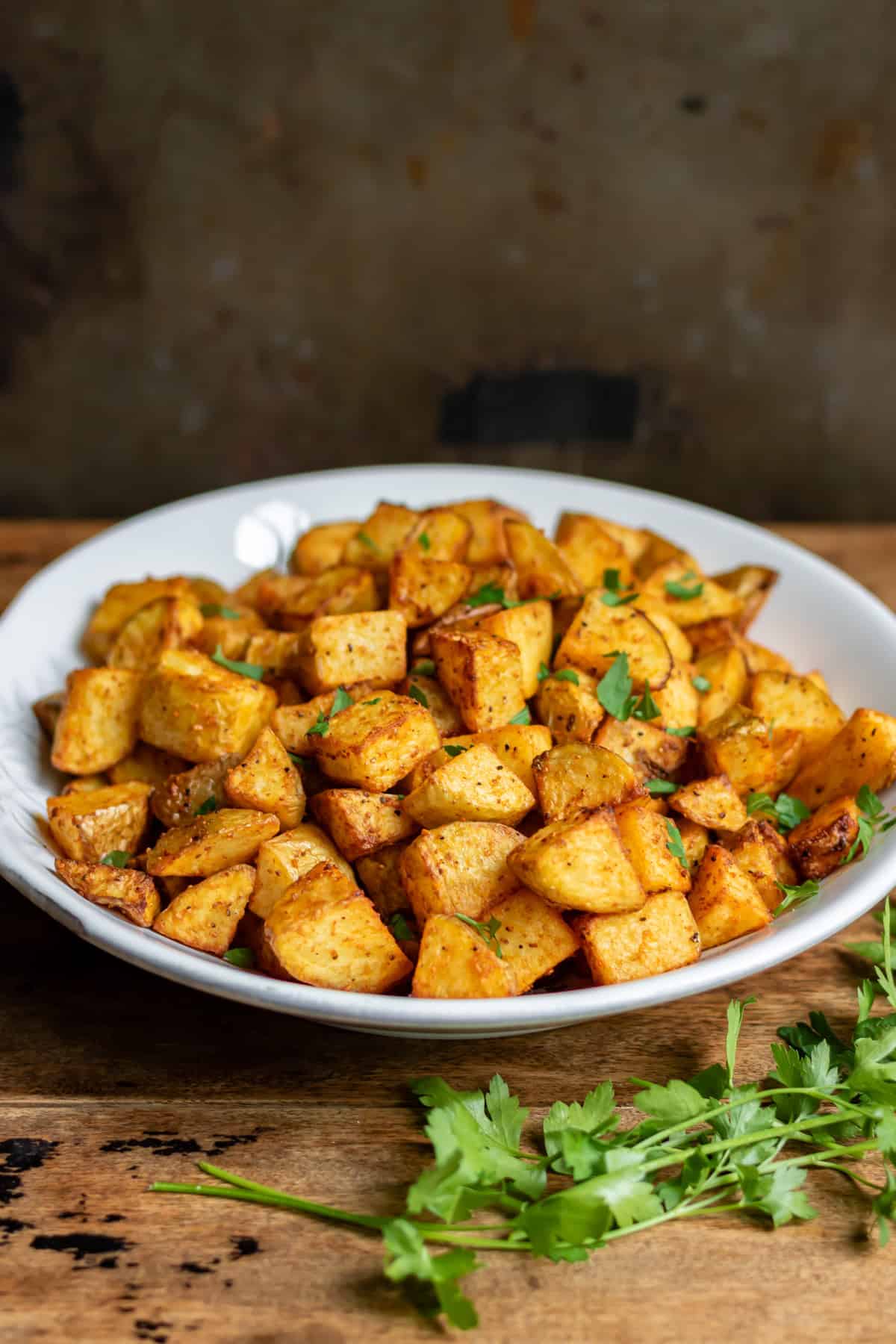 Side view of a table with a dish of crispy air fryer diced potatoes.