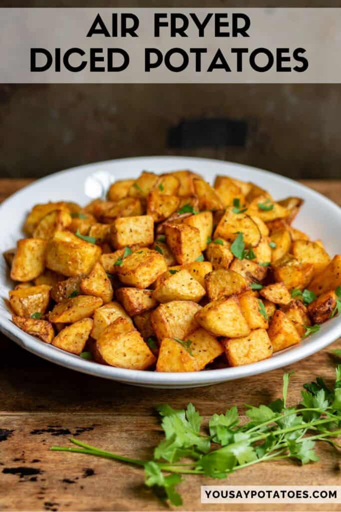 Wooden table with a serving dish of diced potatoes, with text: Air Fryer Diced Potatoes.