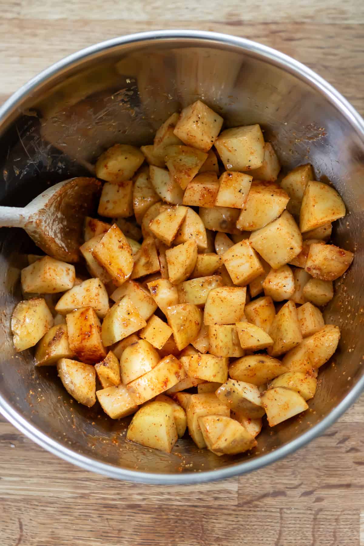 Diced potatoes in a bowl tossed with the seasonings.
