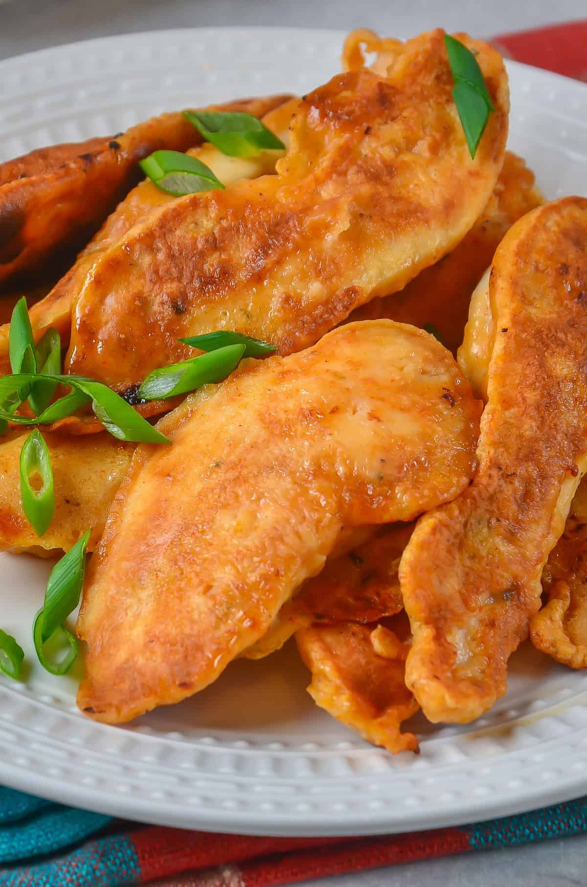 Close up of a pile of battered chicken tenders on a plate.