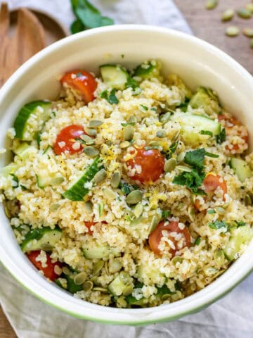 Bowl of bulgur salad with lemon and herbs, pumpkin seeds and vegetables.