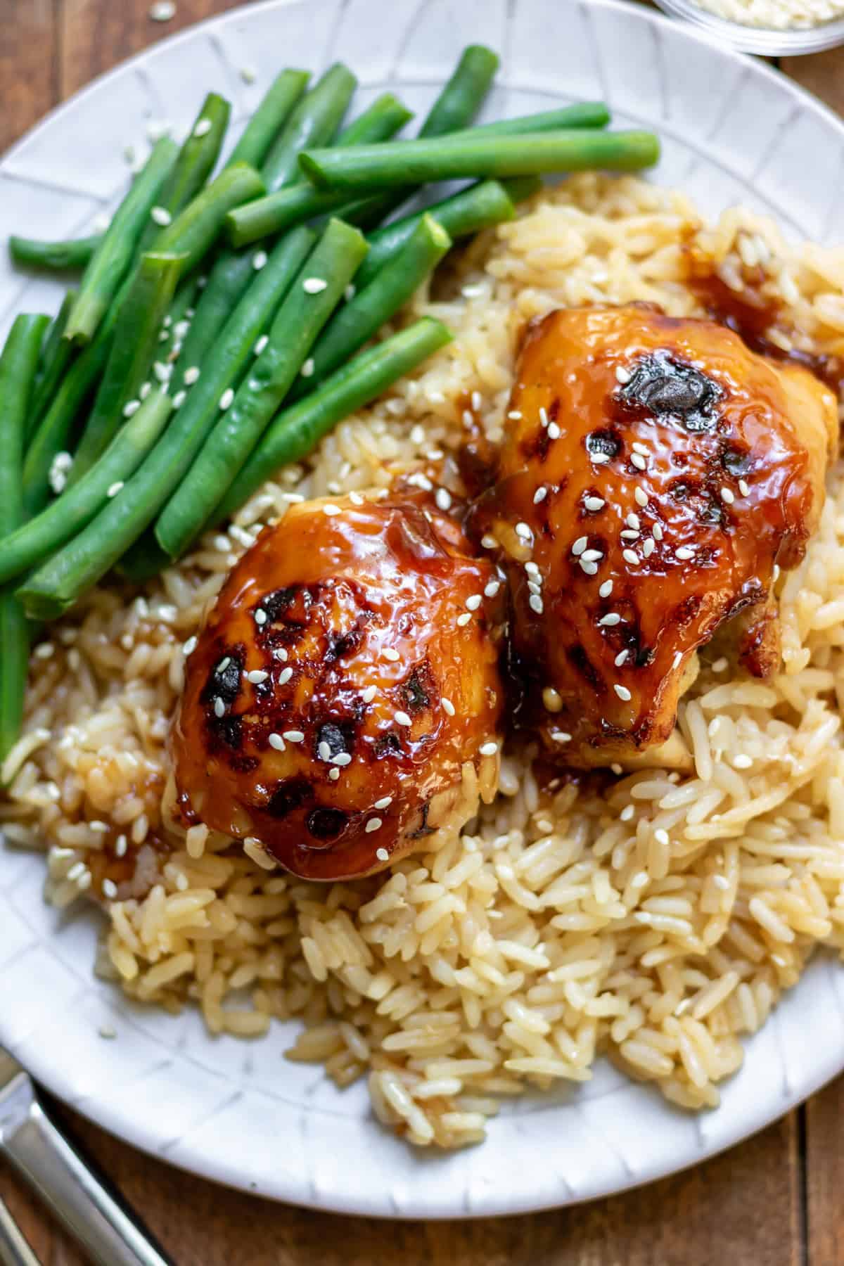 A plate with green beans with sticky honey soy baked chicken and rice.