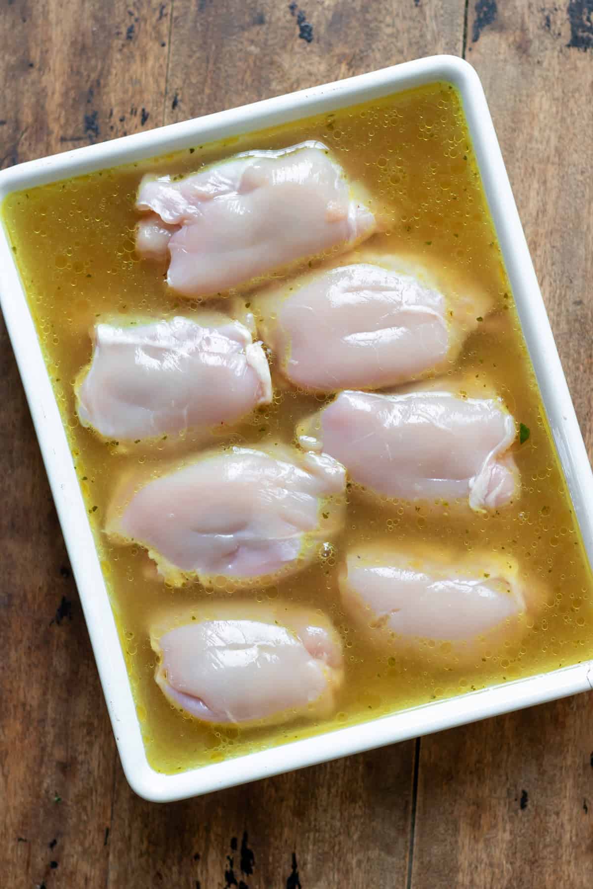 Chicken thighs added to the rice and stock in the baking dish.