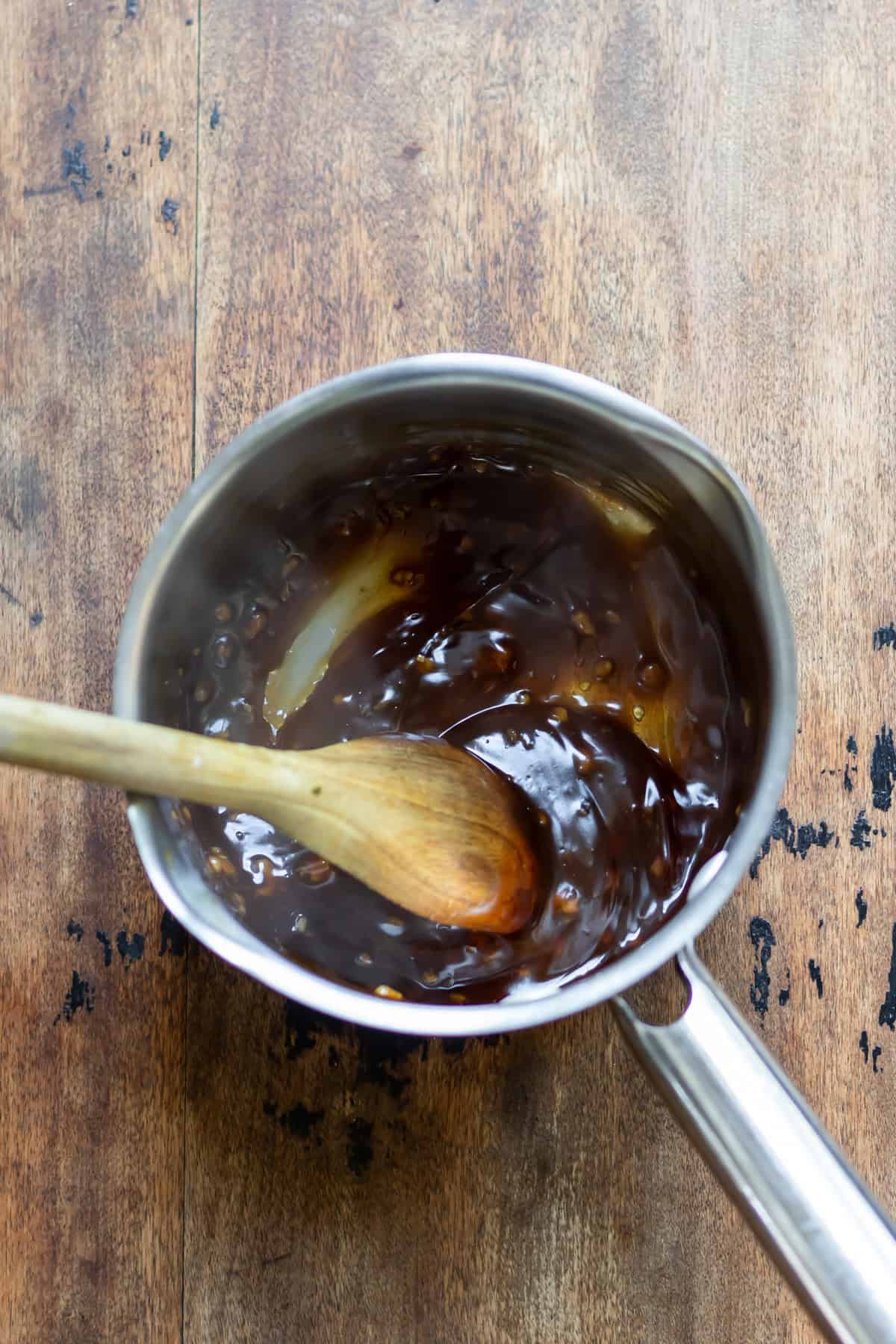 Stirring the sticky honey soy sauce in a saucepan.