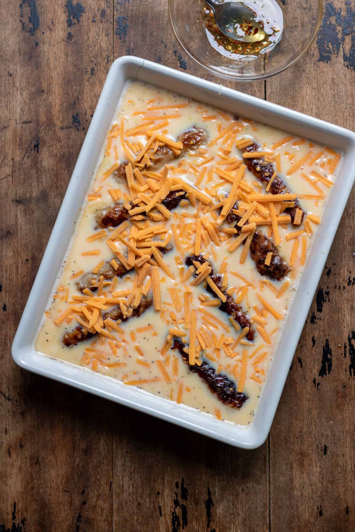 Half of the shredded cheddar cheese sprinkled into the baking dish.