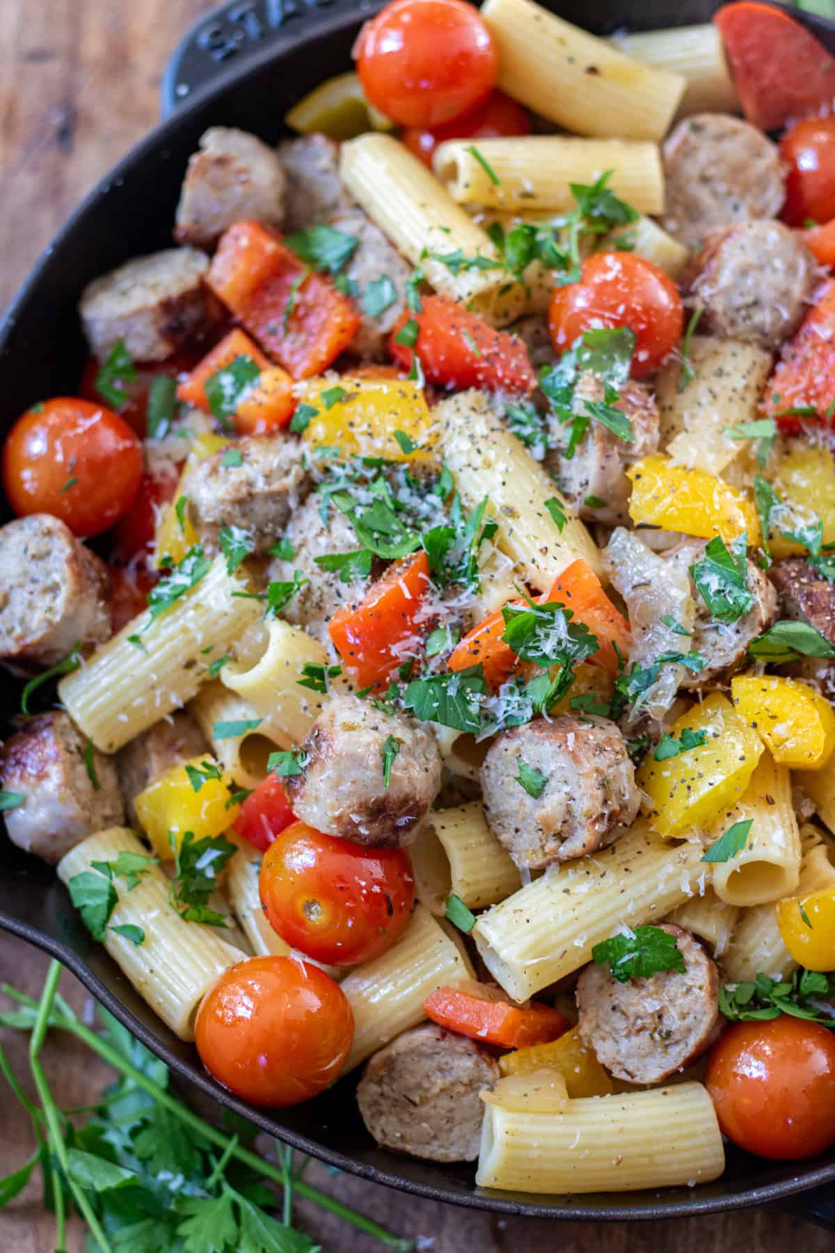 Close up of a skillet with Italian sausages and peppers.