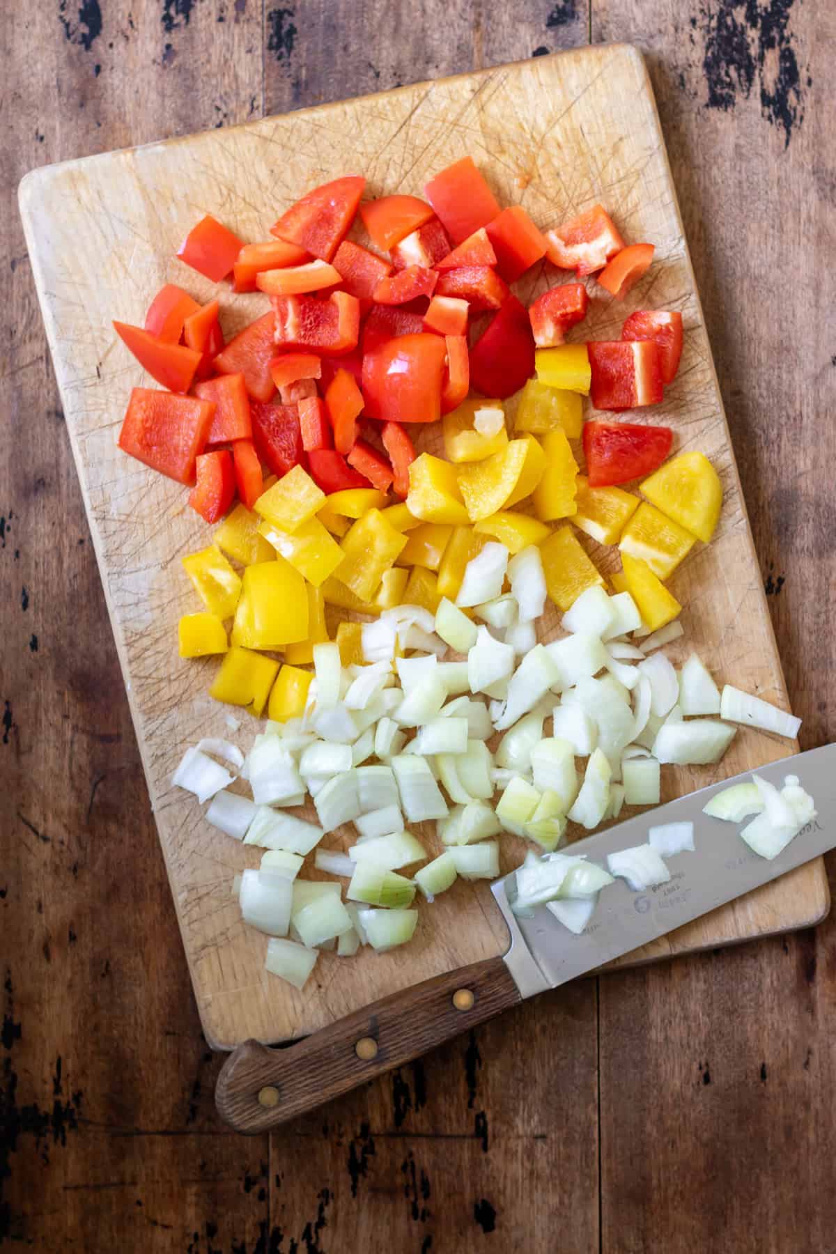 Chopping peppers and onions on a chopping board.