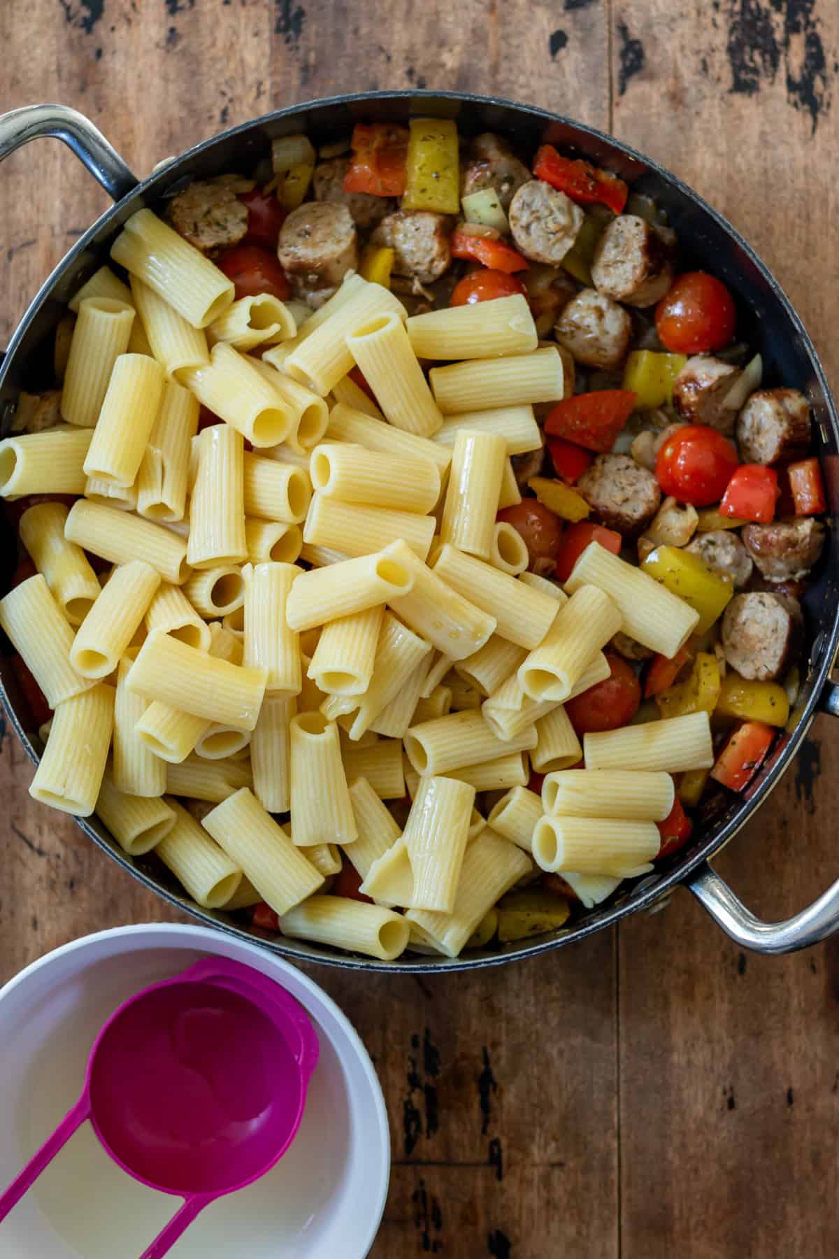 Adding the cooked pasta to the skillet, along with some cooking water.