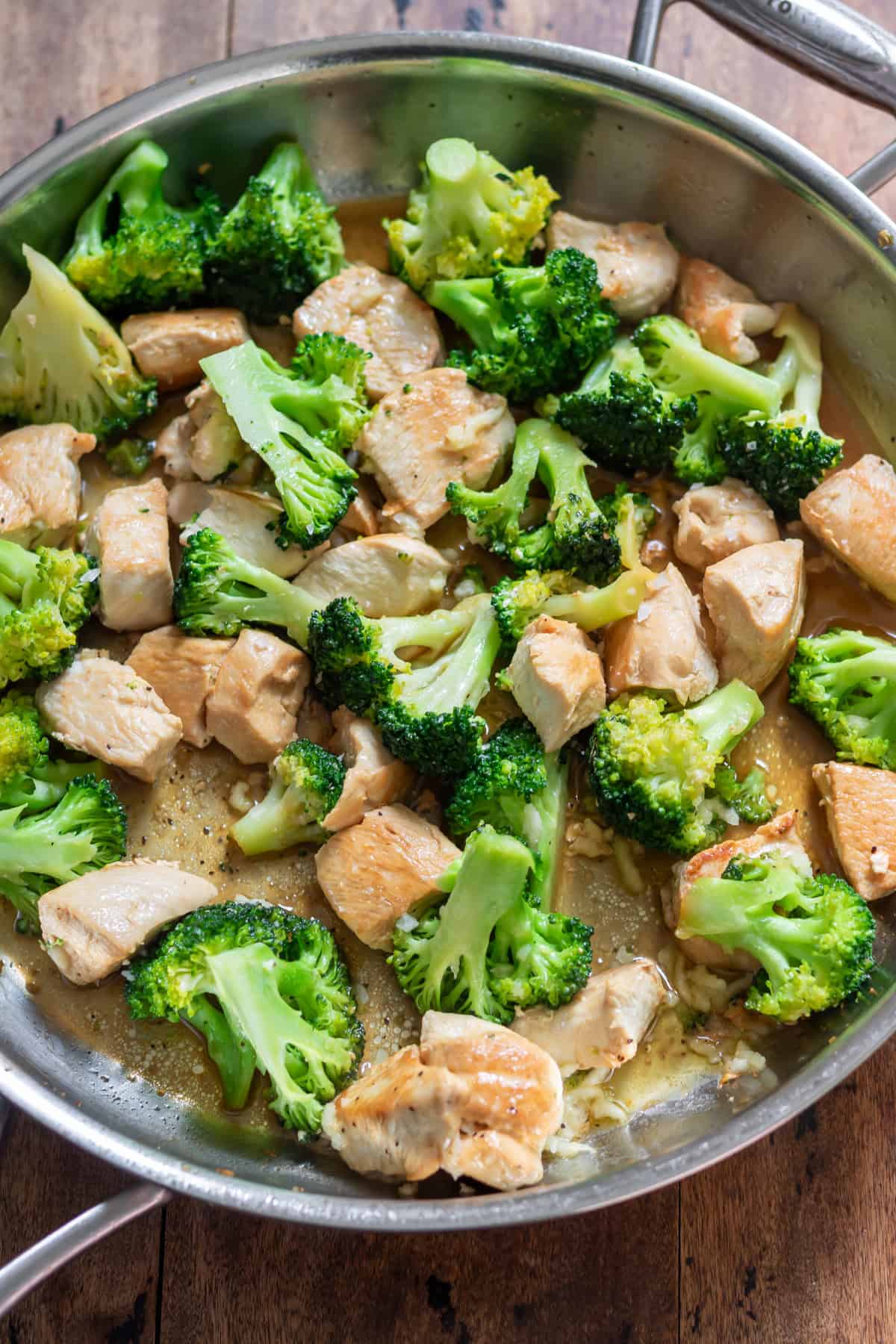 A skillet of chicken and broccoli with garlic butter.