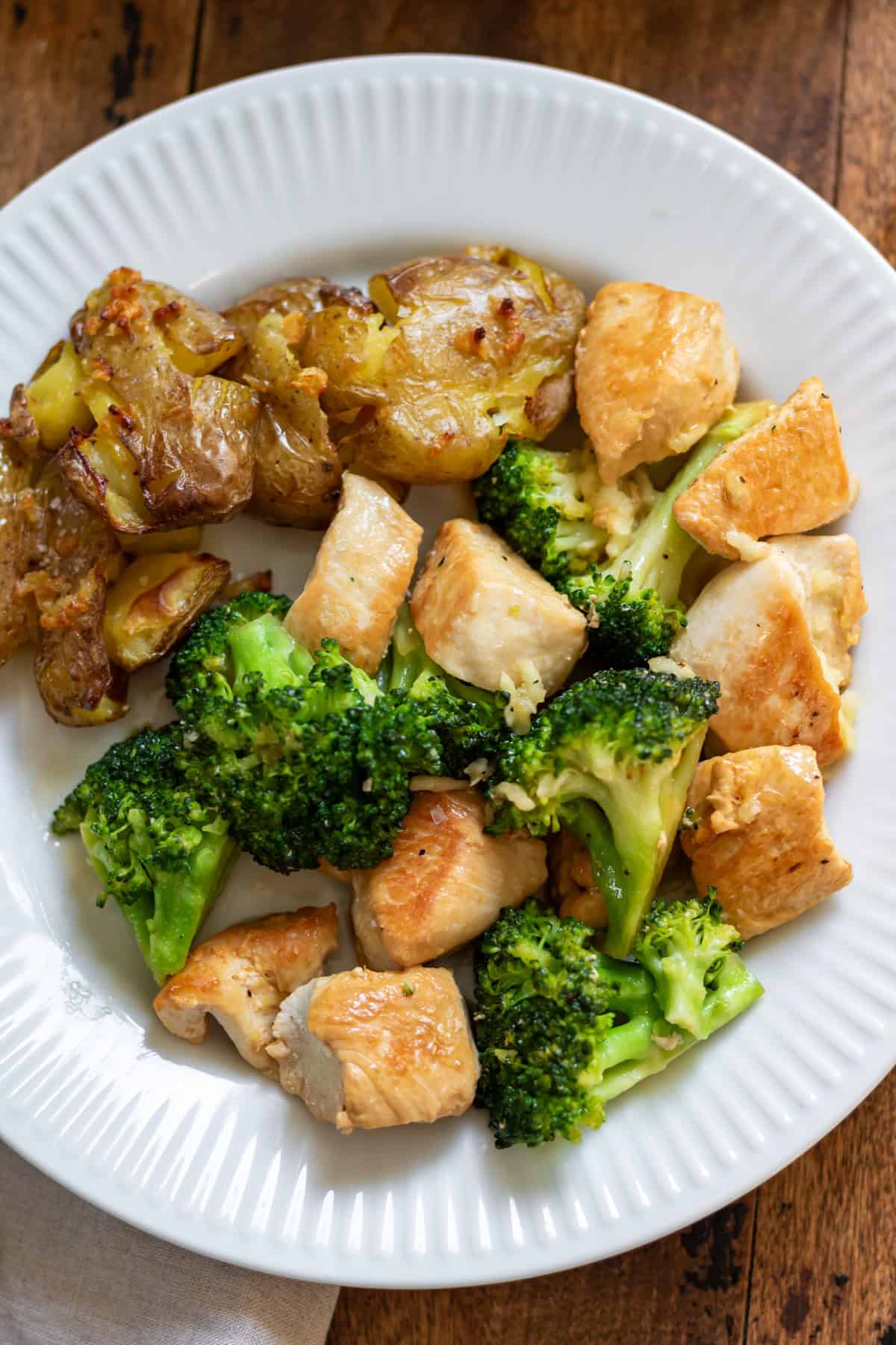 Close up of a plate of garlic butter chicken and broccoli skillet with roasted potatoes.