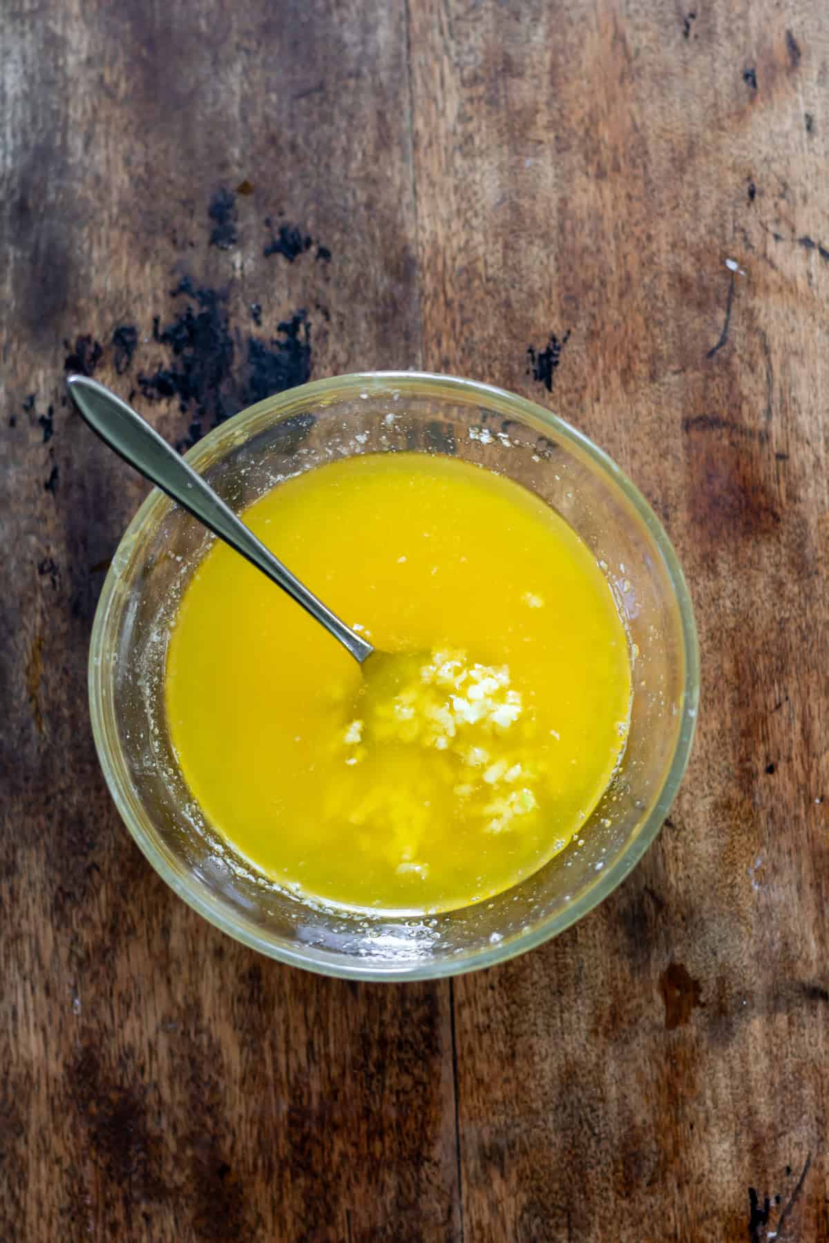 Stirring minced garlic into melted butter.