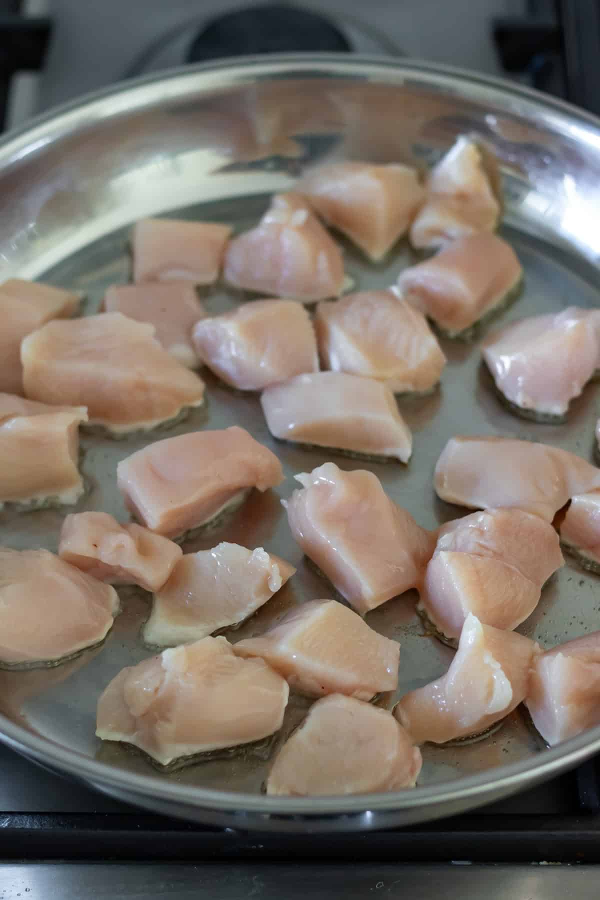 Frying cubes of chicken breast.