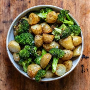 A bowl of garlic roasted broccoli and potatoes.