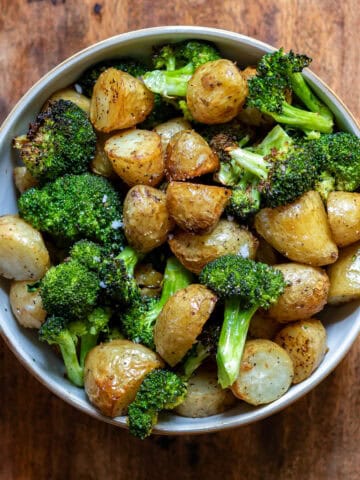 A bowl of garlic roasted broccoli and potatoes.