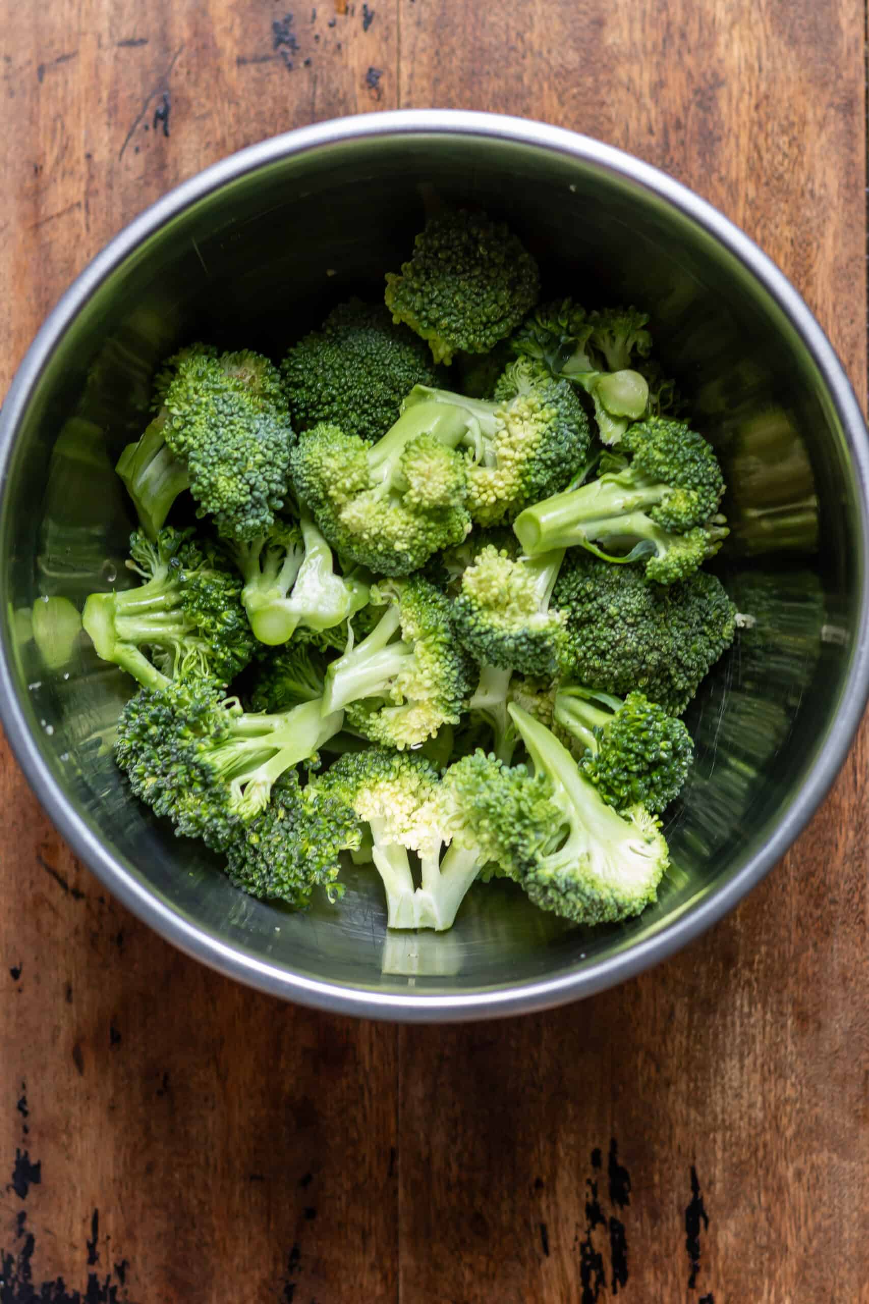 Broccoli florets in a bowl with oil.