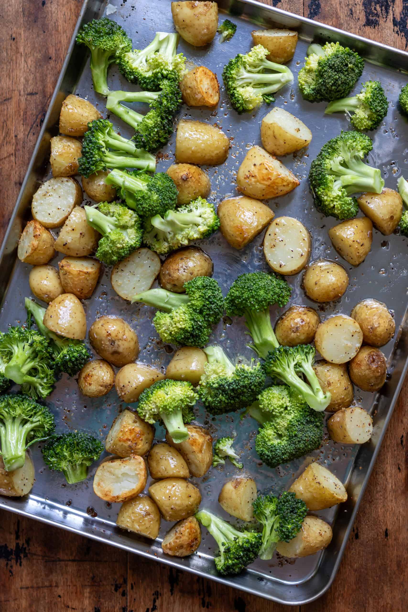 Broccoli added to the baking sheet with partially roasted potatoes.