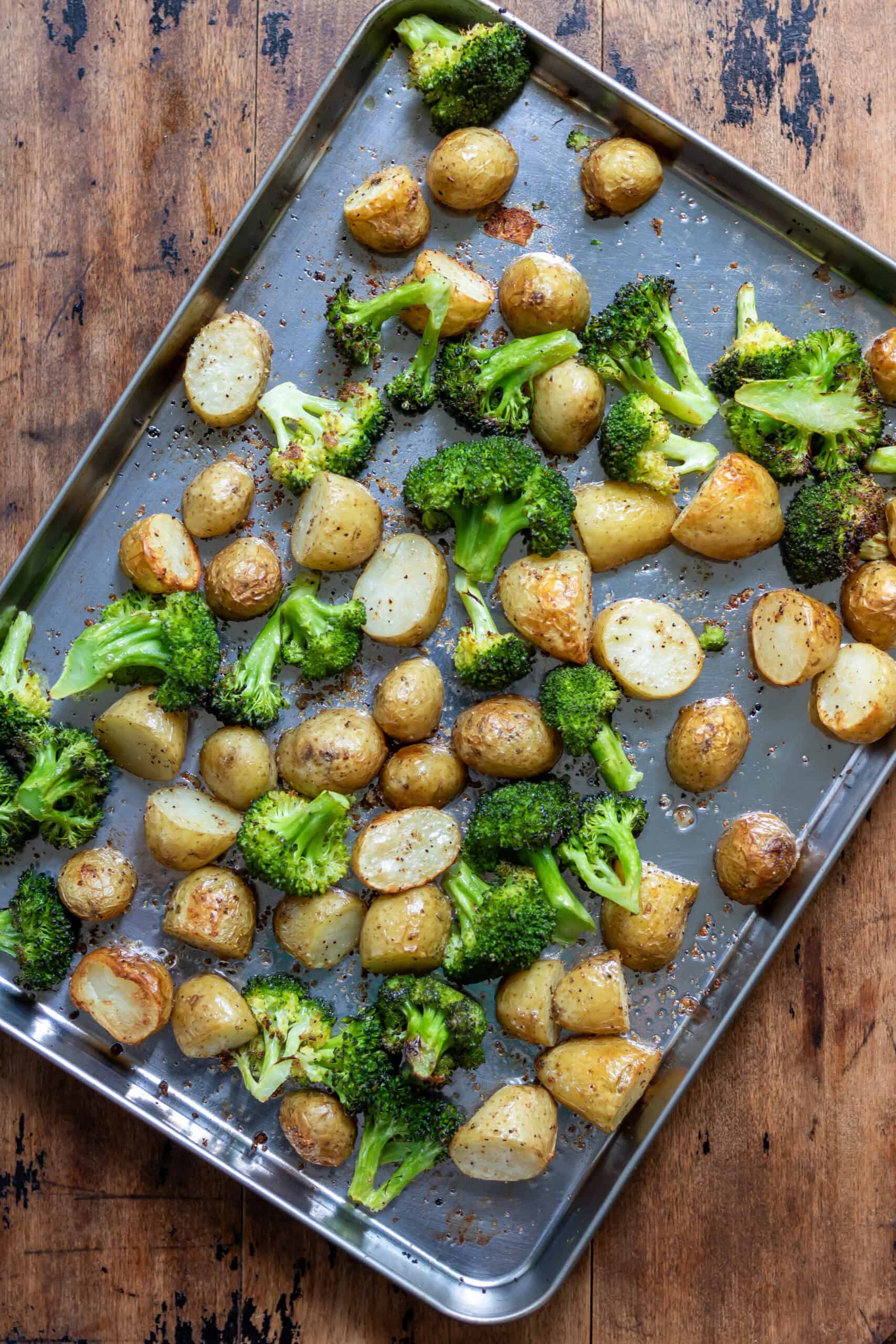 Garlic roasted potatoes and broccoli on a baking sheet.