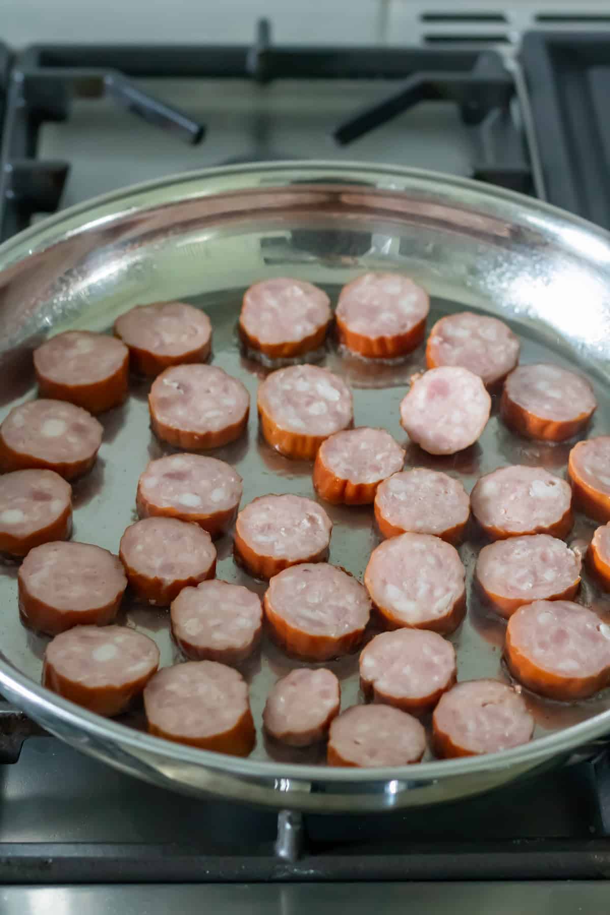 Sliced smoked sausages in a pan.