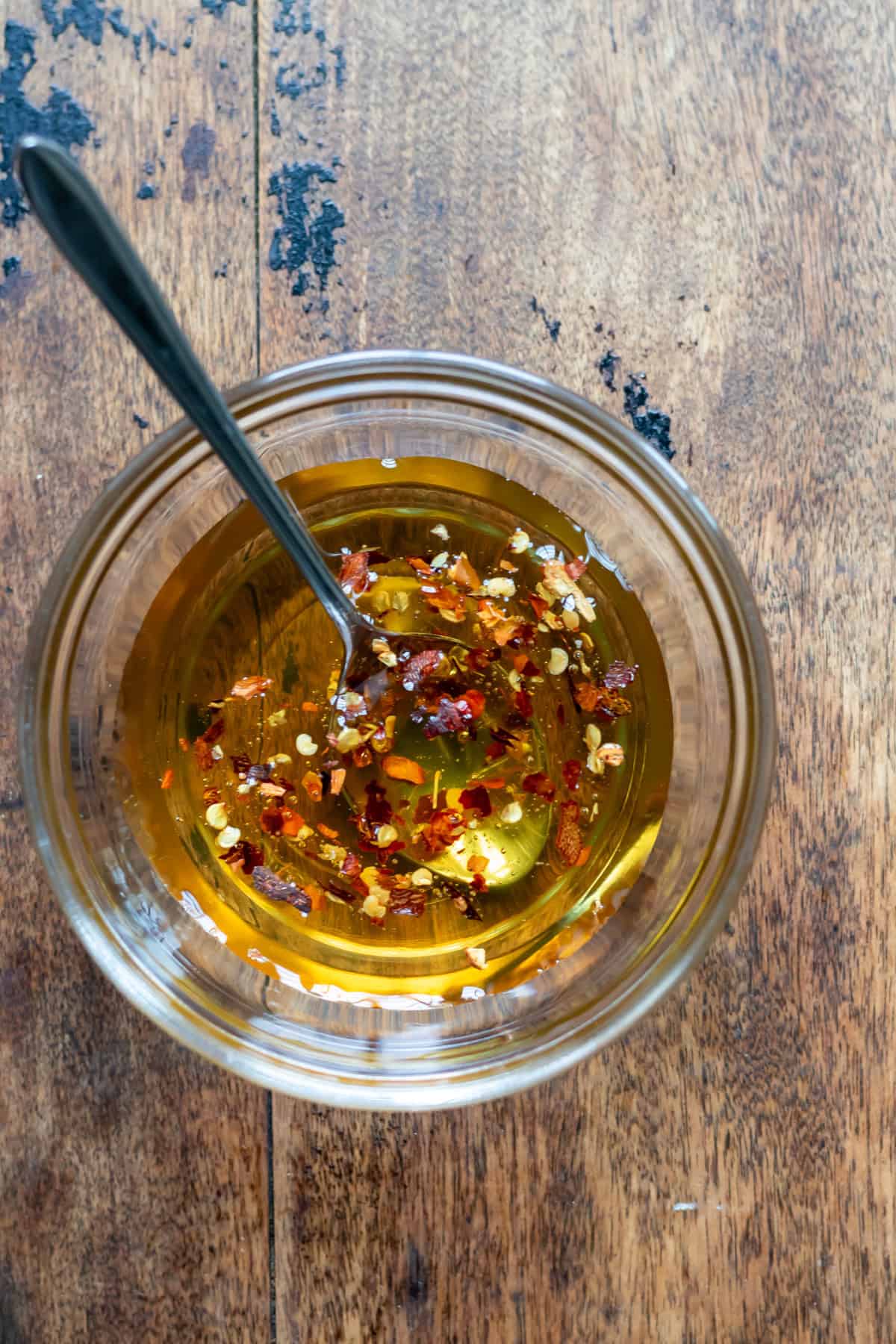 Stirring the chilli pepper flakes into the honey to make hot honey.