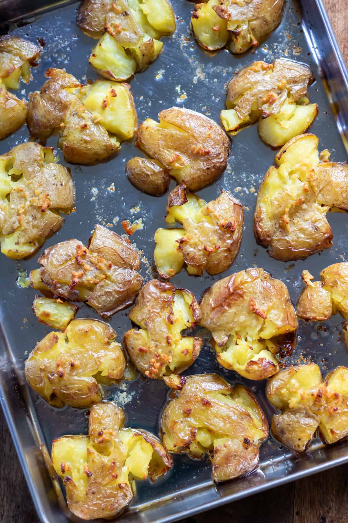 A baking sheet with smashed roasted baby potatoes with garlic butter.