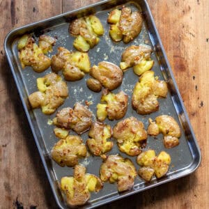 Smashed roasted potatoes on a baking sheet.