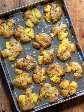 Smashed roasted potatoes on a baking sheet.