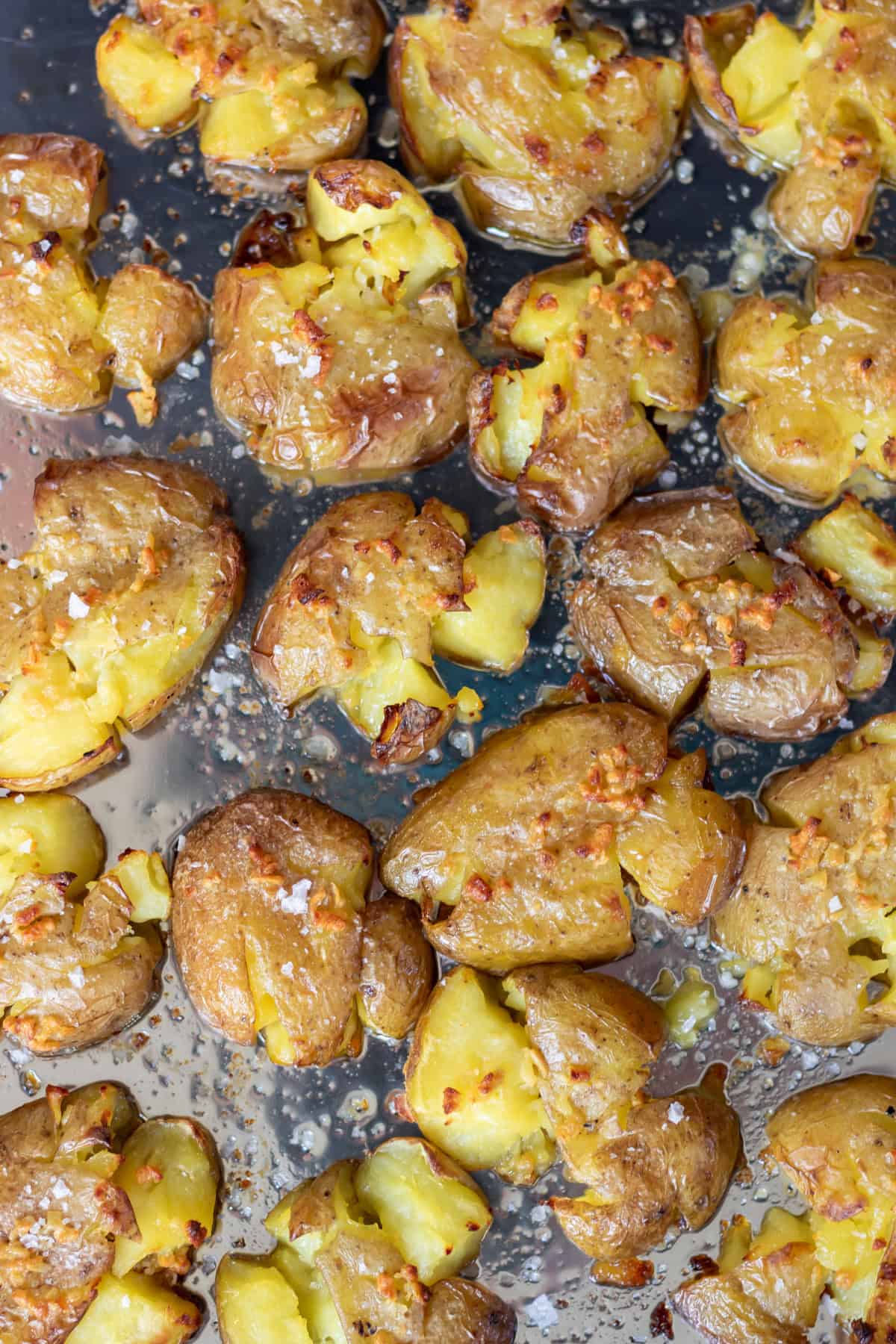 A baking sheet of smashed roasted potatoes with garlic butter and sea salt.