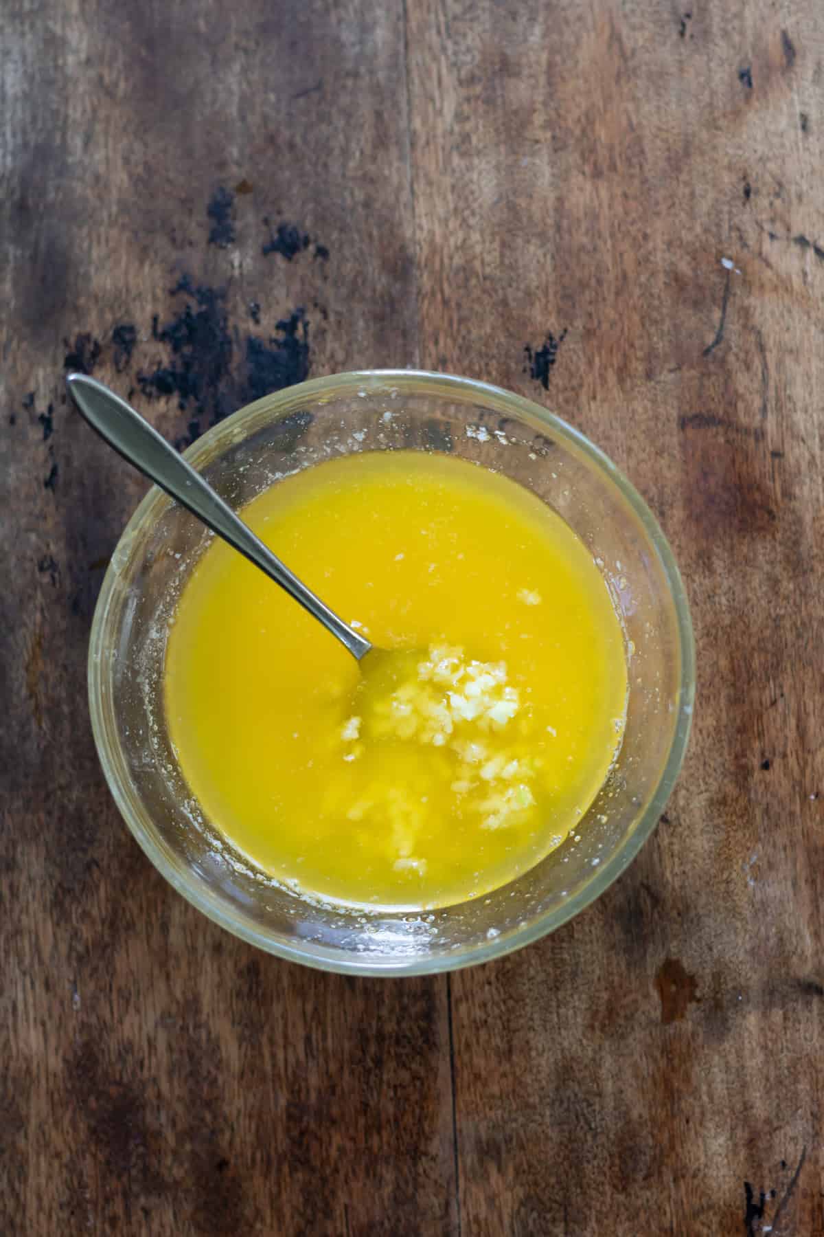 Stirring minced garlic into melted butter.