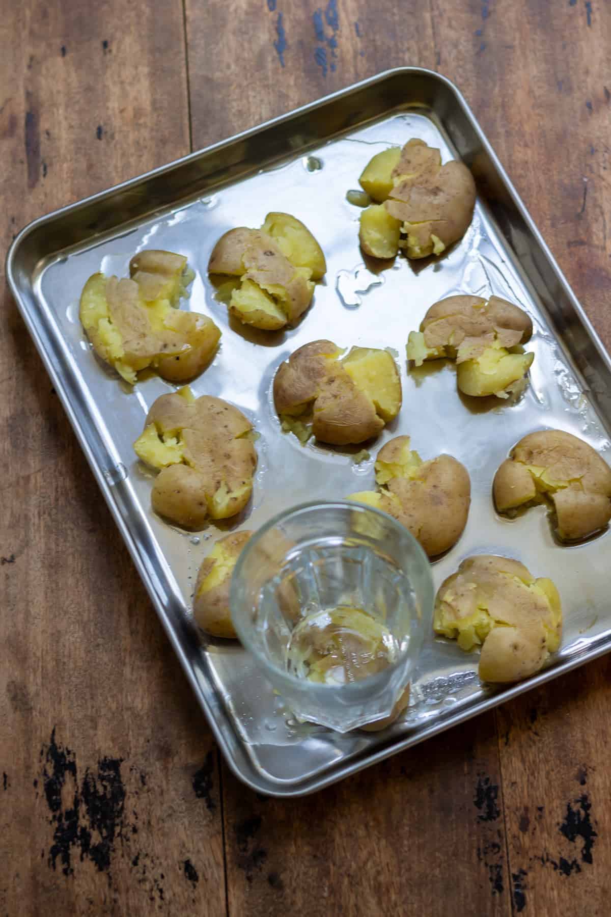 Using a glass to crush the boiled baby potatoes.