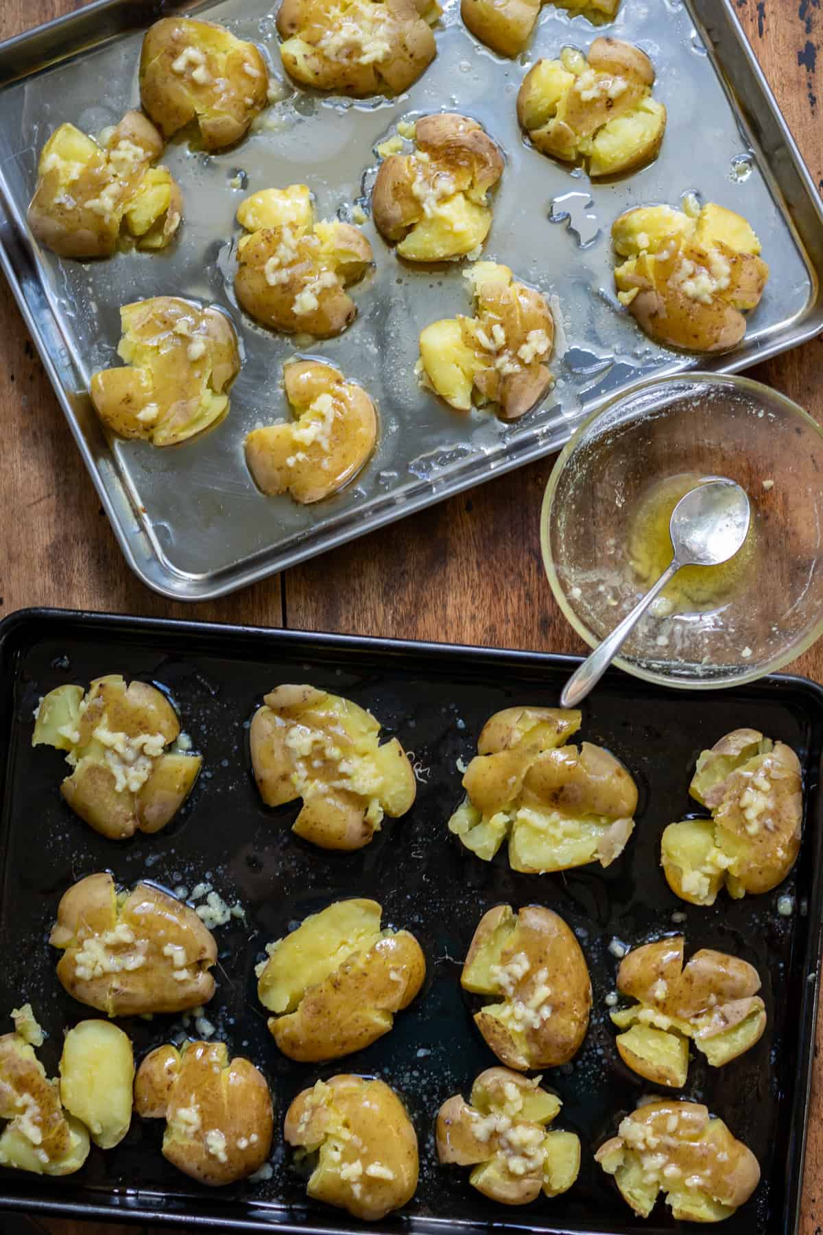 Drizzling garlic butter onto the smashed potatoes.
