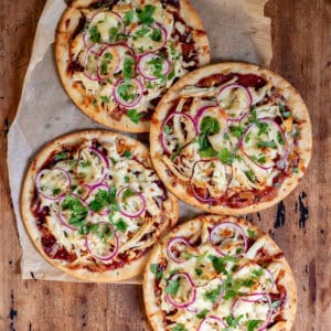 A wooden table with four bbq chicken flatbreads.