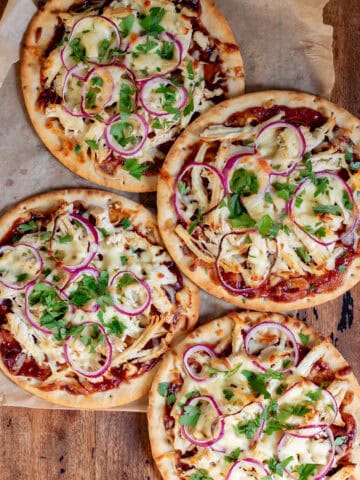 A wooden table with four bbq chicken flatbreads.