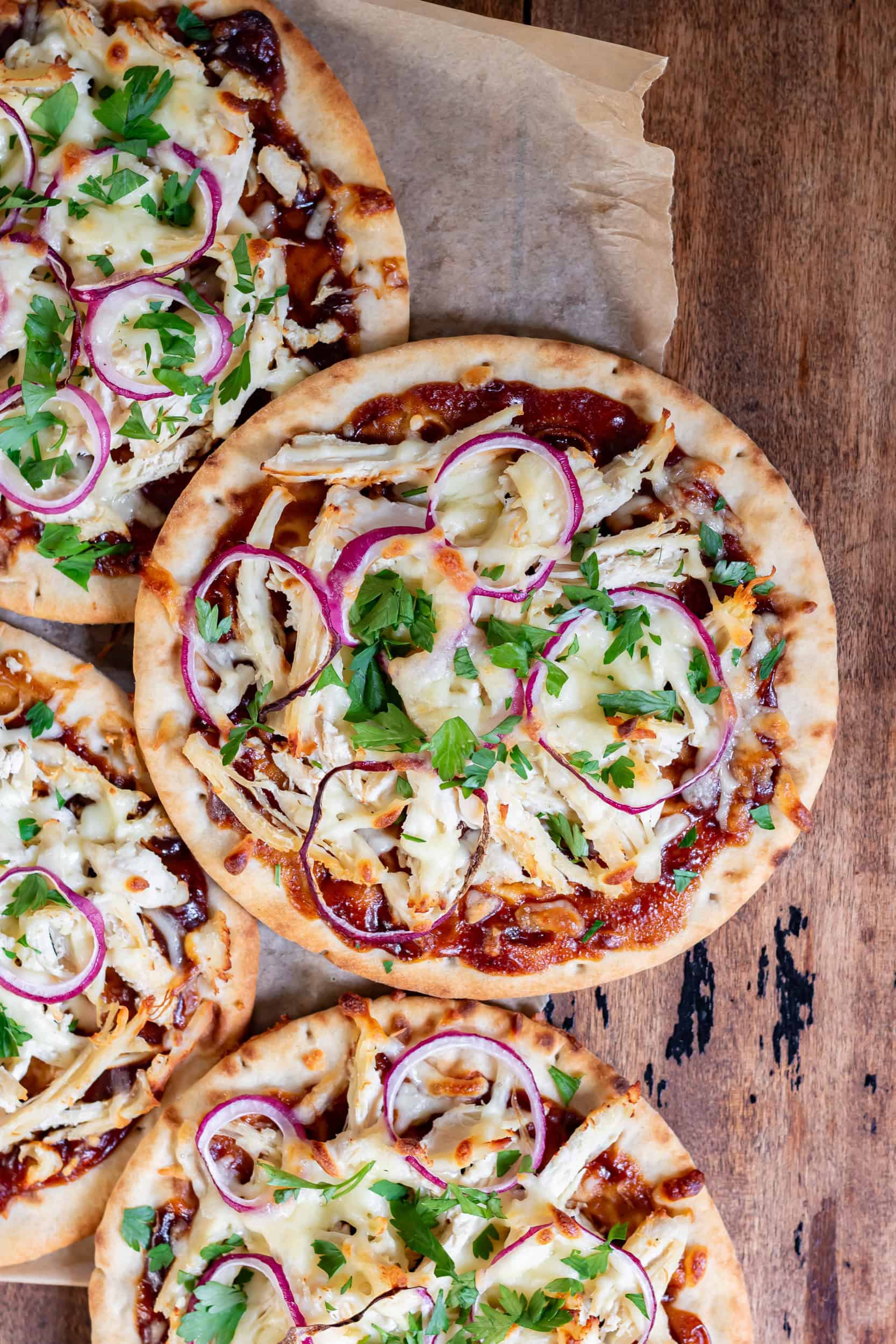 Close up of a barbecue chicken flatbread on a pile of more of them.