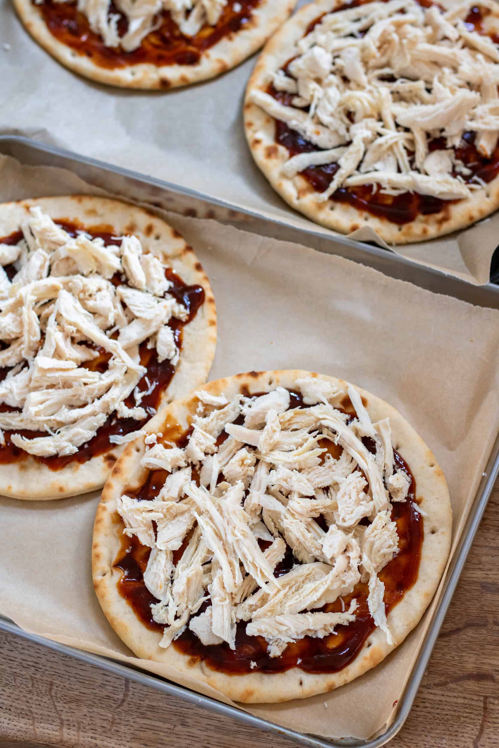 Piling shredded chicken onto the bbq flatbreads.