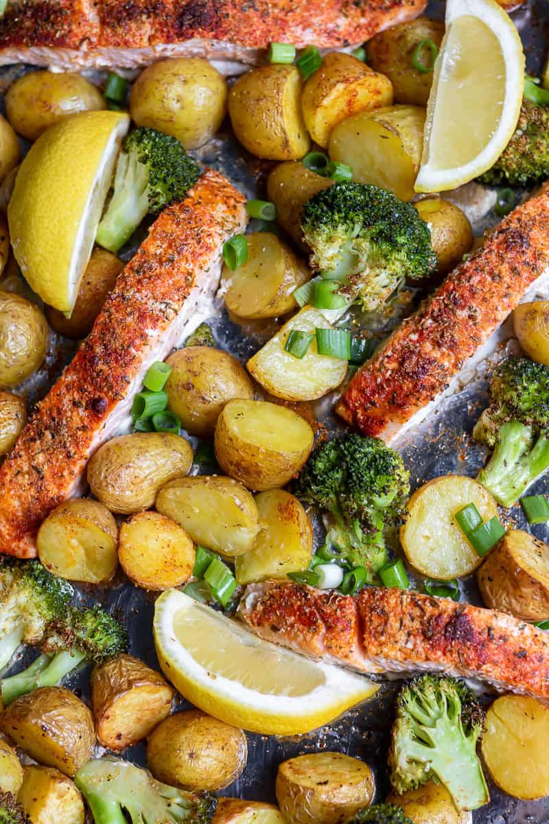 Sheet pan salmon, potatoes and broccoli, with wedges of lemon and scallions.