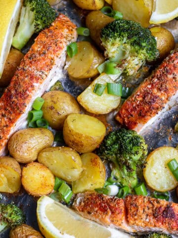 Sheet pan salmon, potatoes and broccoli, with wedges of lemon and scallions.