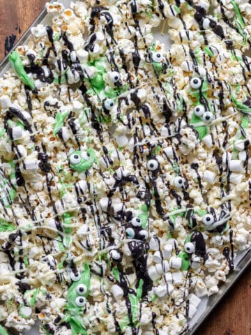 Tray of Halloween Monster Popcorn drizzled with coloured white chocolate and sprinkled with candy eyes and mini marshmallows.